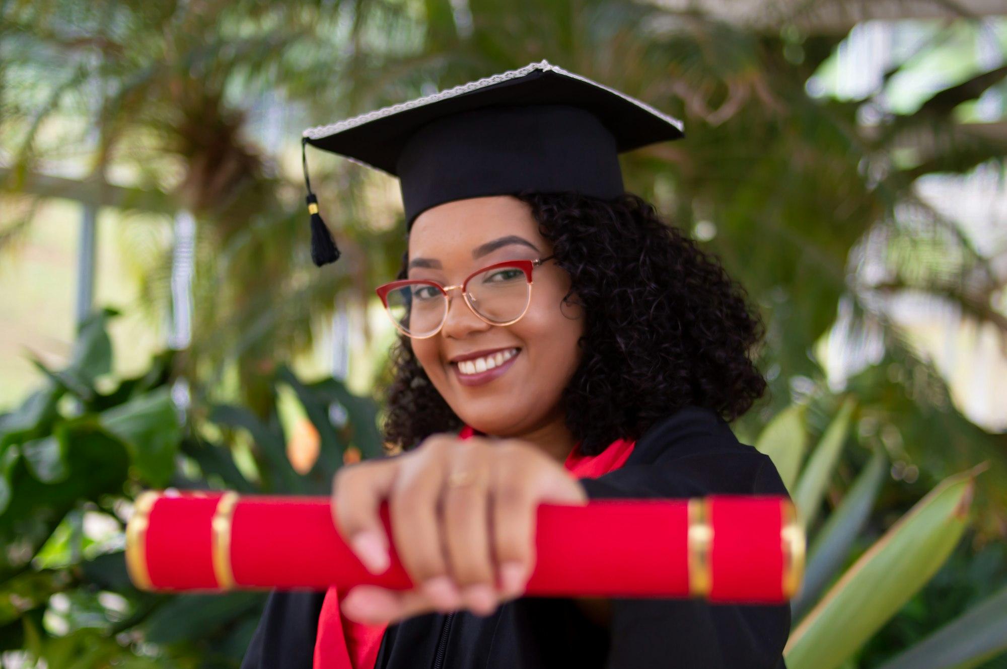 Une jeune diplômée souriante qui tend son diplôme