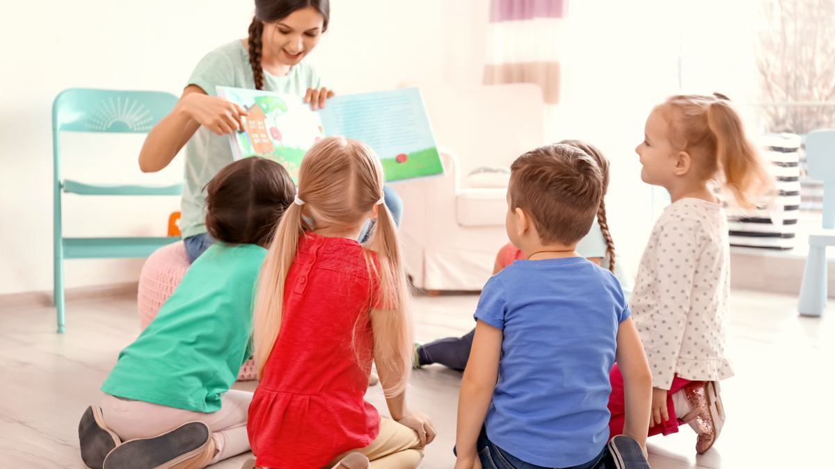 Professionnelle de la petite enfance lisant un album à un groupe de jeunes enfants
