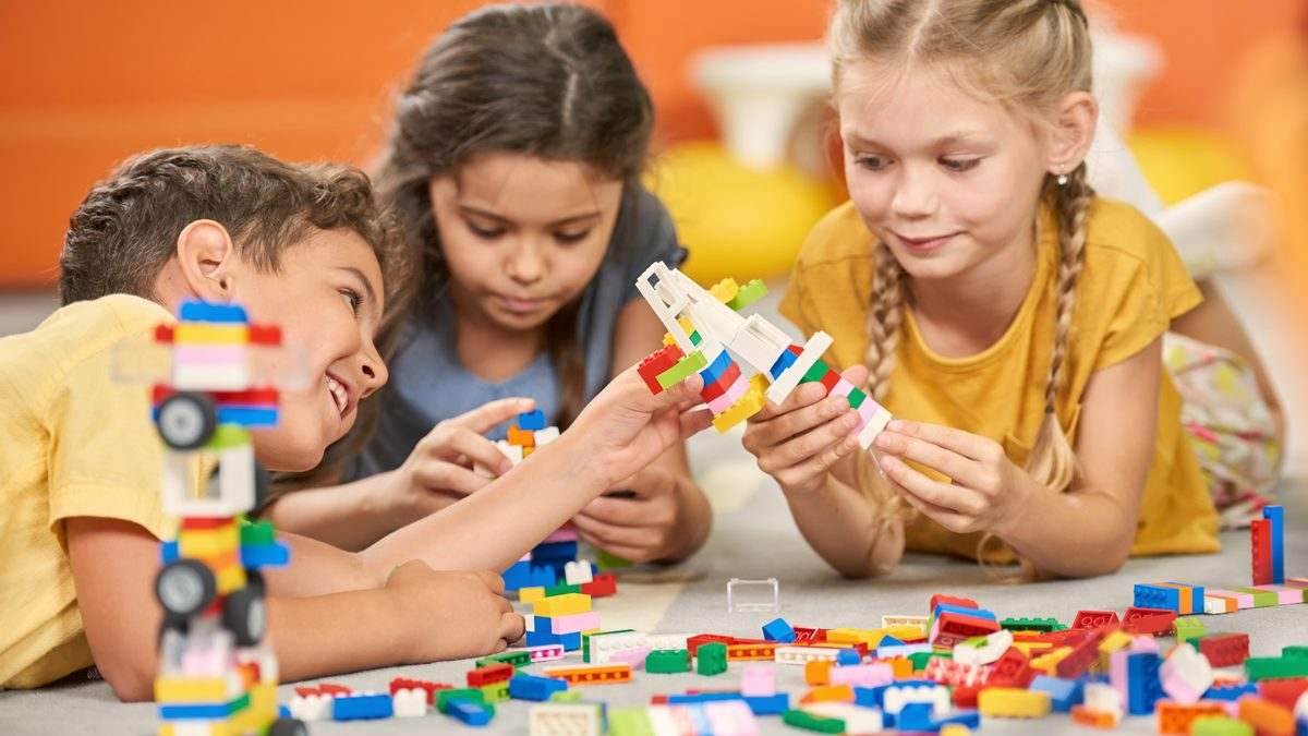 Trois jeunes enfants construisant ensemble avec des briques de couleur