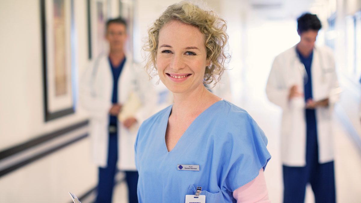 Professionnelle de santé souriante dans le couloir lumineux d'un établissement de soins