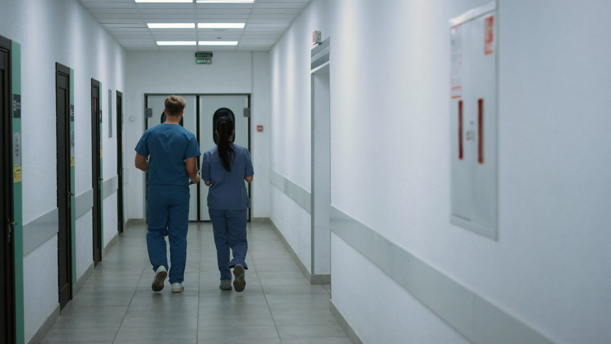 Deux professionnelles en tenue de travail s'éloignant dans un couloir d'établissement de soins