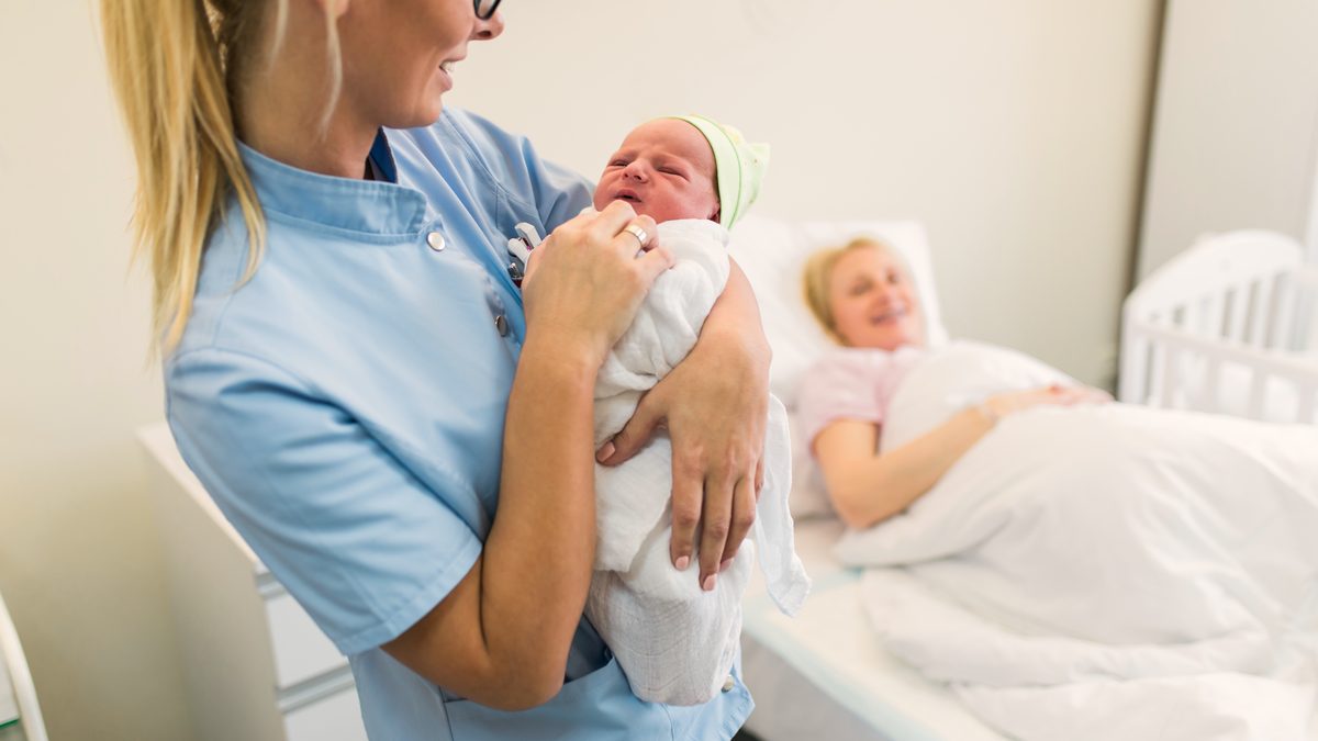 Professionnelle de santé portant un nouveau-né dans un service de maternité