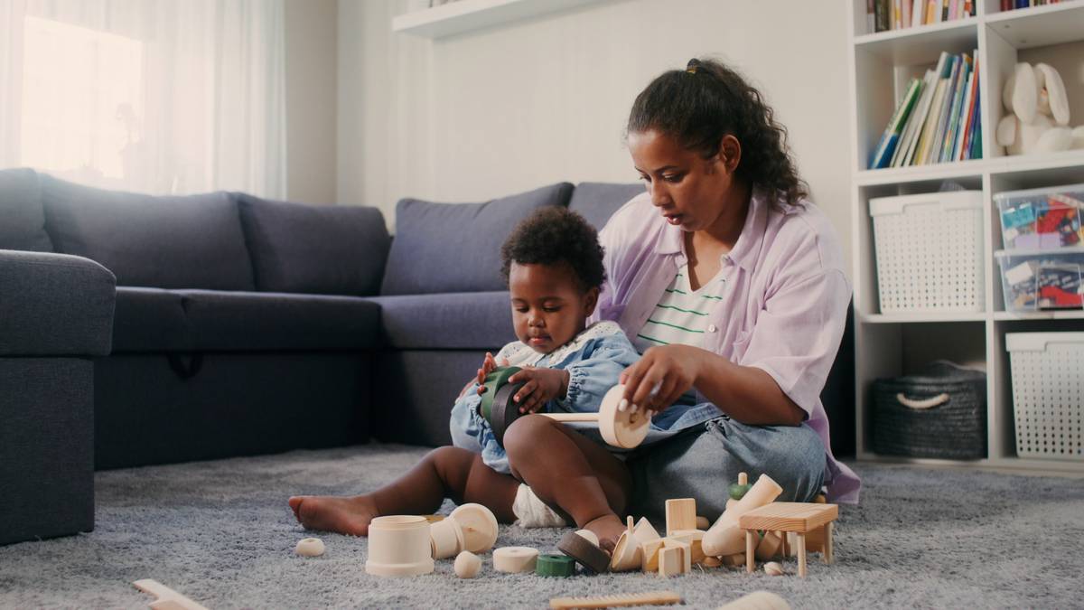 Professionnelle de la petite enfance jouant avec un jeune enfant dans un salon, accueil au domicile