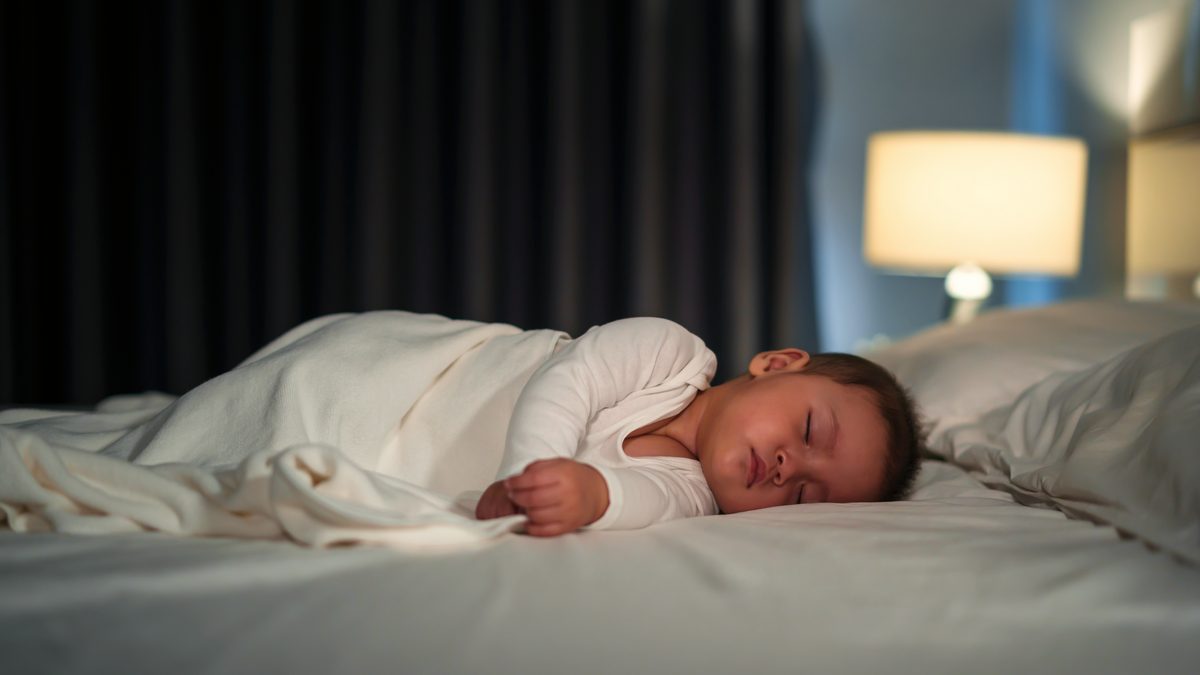Petit enfant endormi paisiblement dans son lit, dans une chambre à la lumière douce