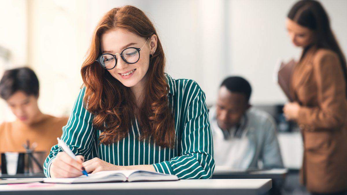 Adulte en formation prenant des notes dans un cahier pendant un cours en salle