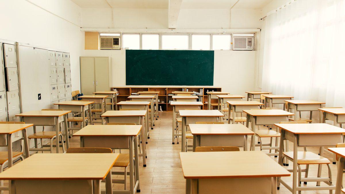 Salle de classe vide et lumineuse avec tables en bois et tableau vert