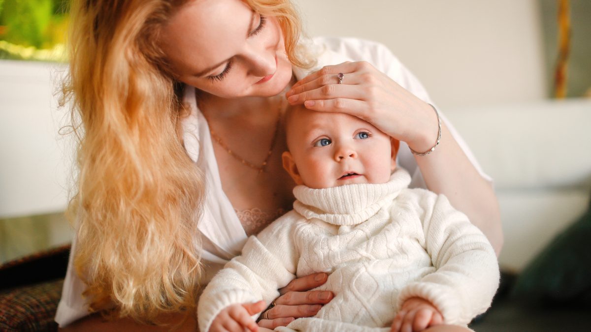 Une maman pose la main sur le front d'un bébé pour vérifier sa température
