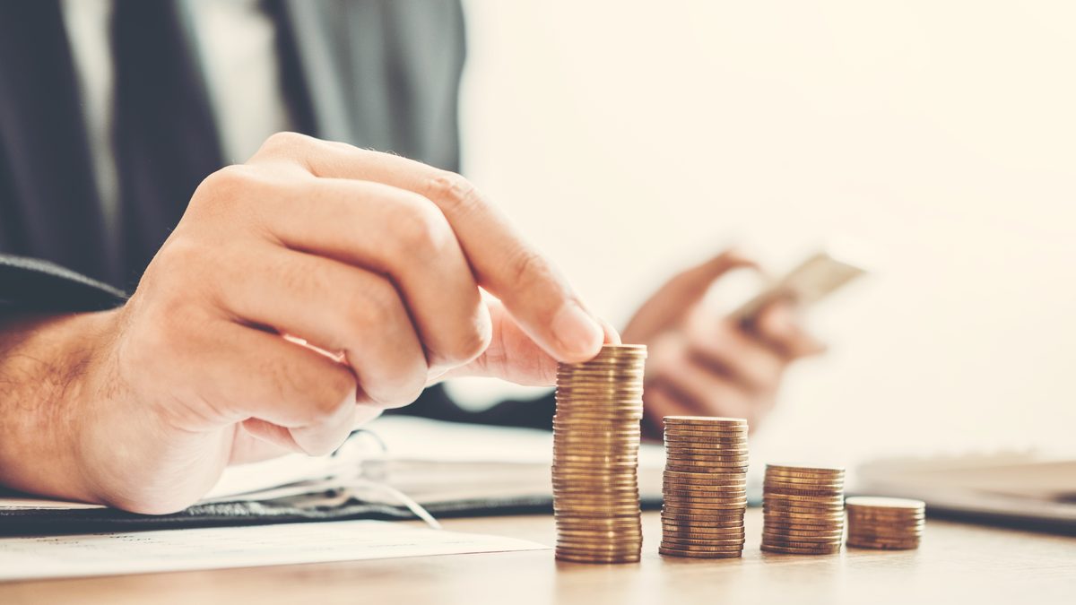 Main posant des pièces en colonnes à côté d'une calculatrice pour établir le budget d'une formation CAP AEPE