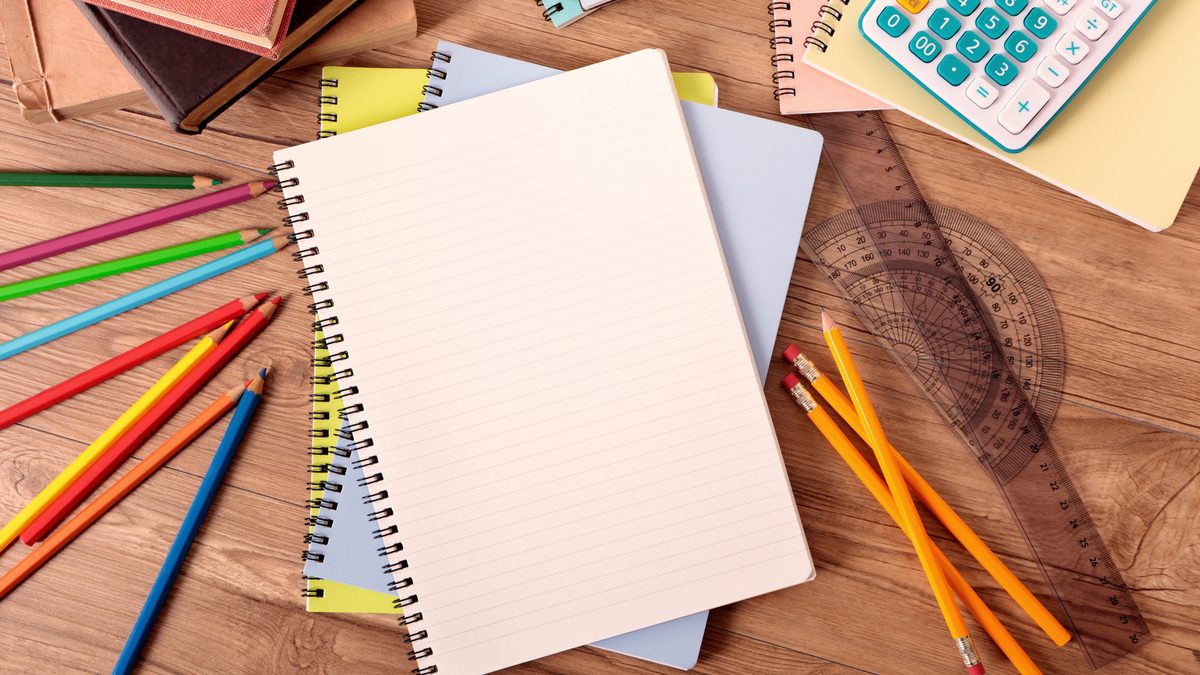Bureau d'étudiante avec un cahier ouvert, des livres et des crayons