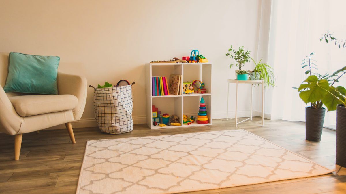Espace de jeu lumineux d'une crèche avec étagère de jouets, fauteuil et tapis