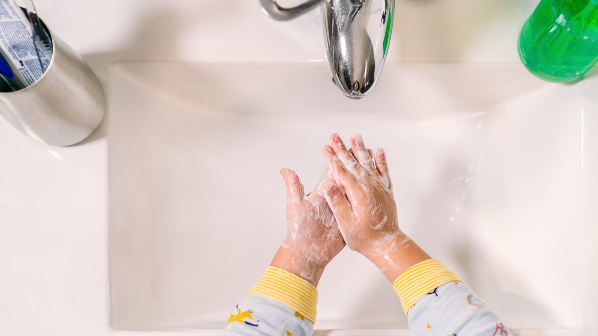 Jeune enfant qui apprend à se laver les mains seul au lavabo
