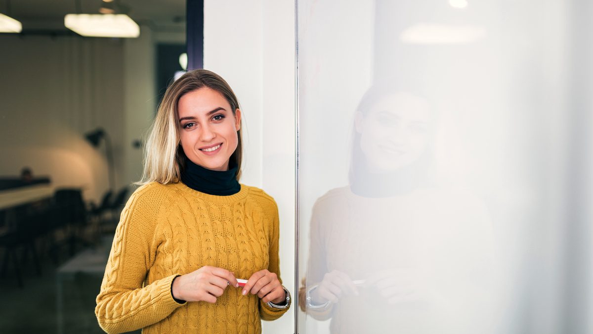 Une formatrice souriante devant un tableau blanc