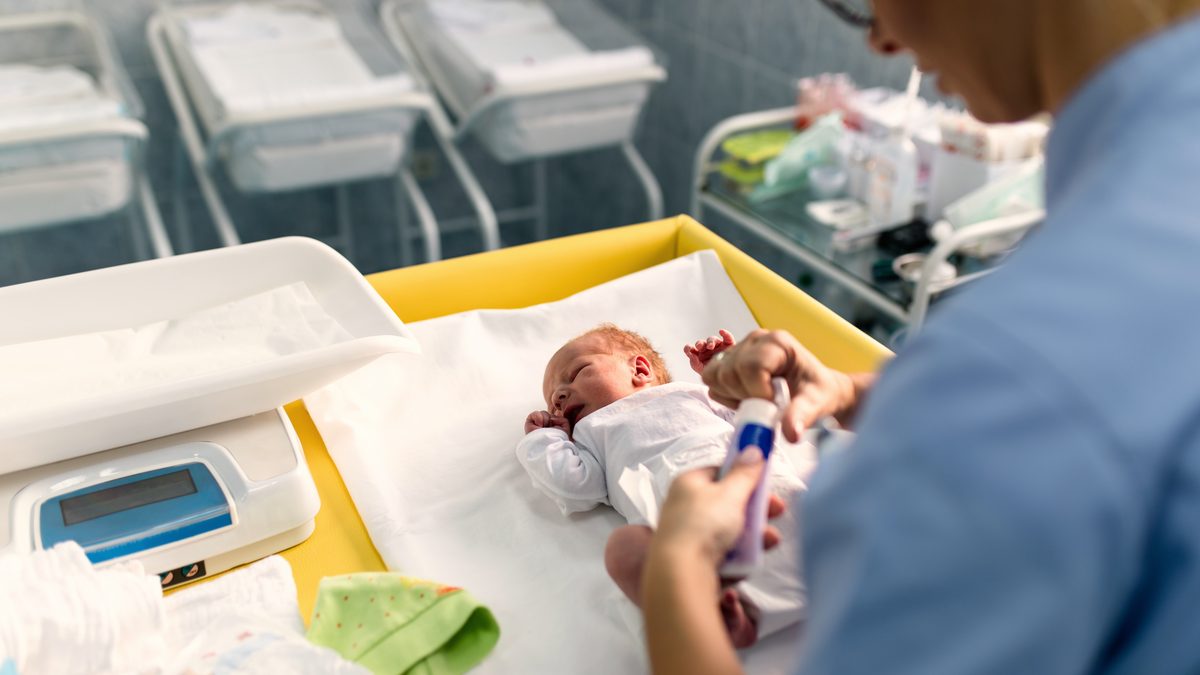 Soignante en maternité pesant et installant un nouveau-né sur une table de soins