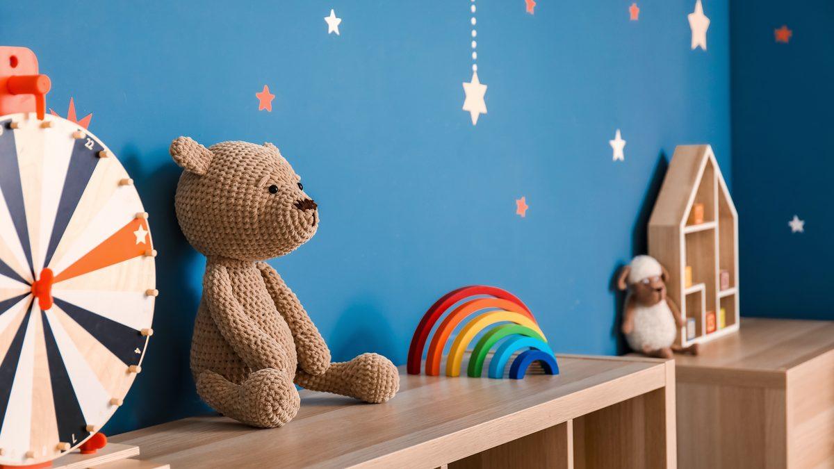 Salle de vie de structure petite enfance avec banc en bois, jouets en bois et étagères basses