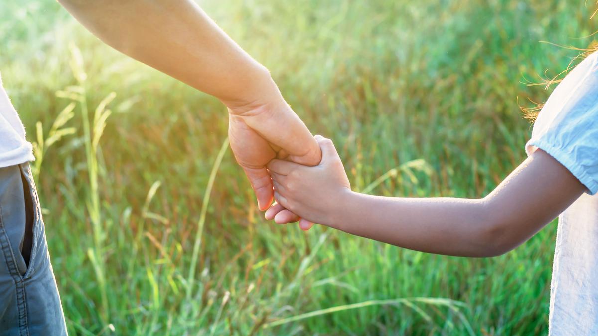 Main d'un adulte tenant doucement la main d'un jeune enfant
