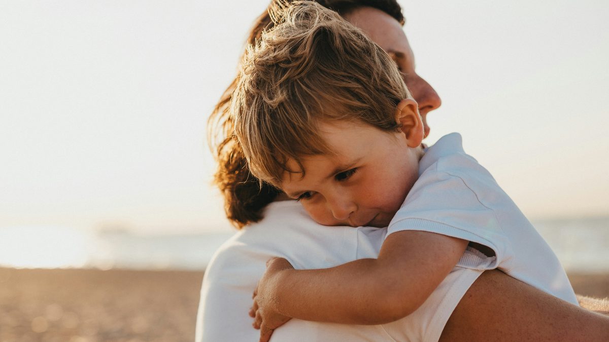 Jeune enfant blotti dans les bras de son parent, rassuré