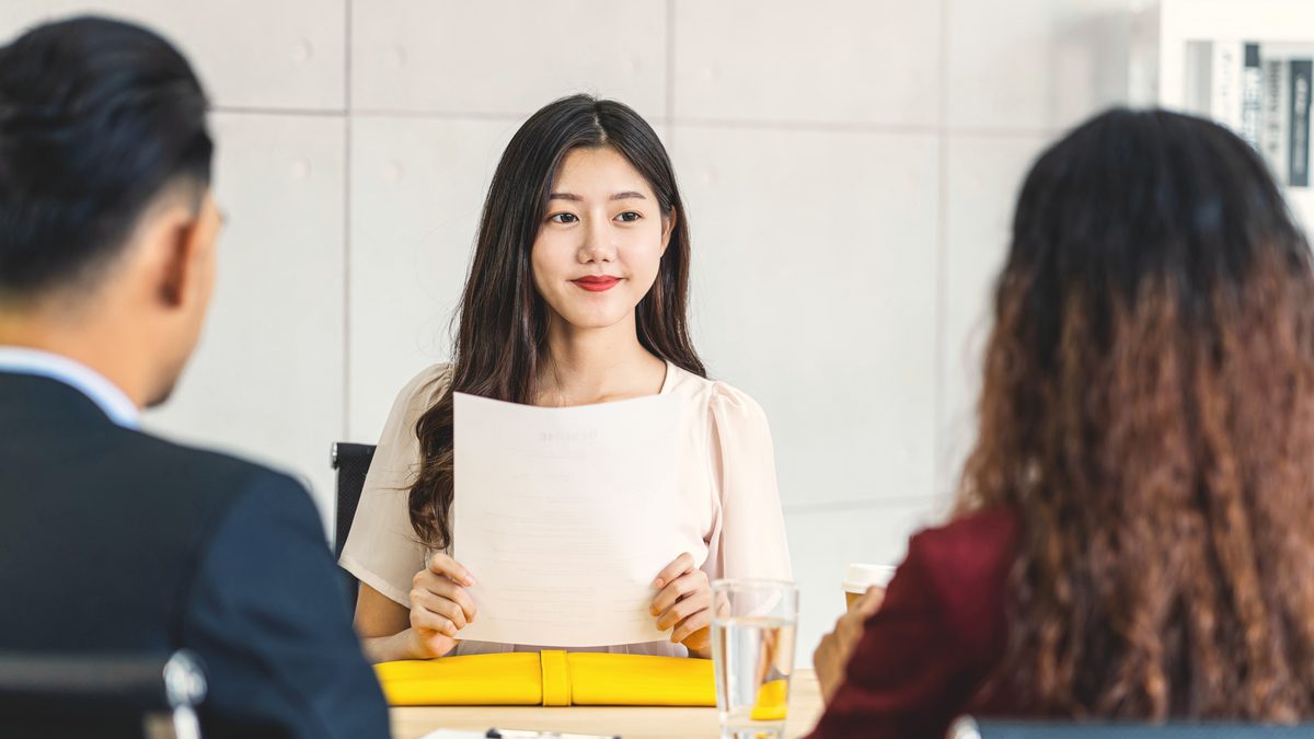 Candidate présentant son dossier devant deux professionnels lors d'un entretien d'examen