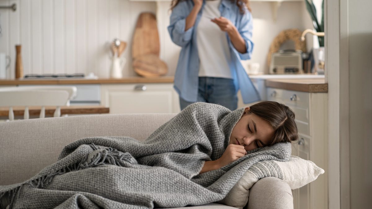 Une petite fille malade est allongée sur un canapé, sa mère au téléphone avec le pédiatre