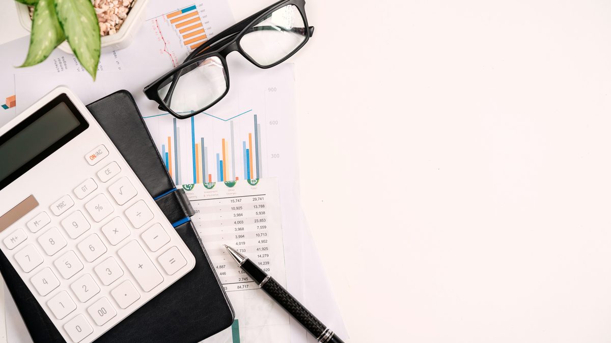 Calculatrice, lunettes et documents chiffr&eacute;s pos&eacute;s sur un bureau pour v&eacute;rifier un bulletin de paie