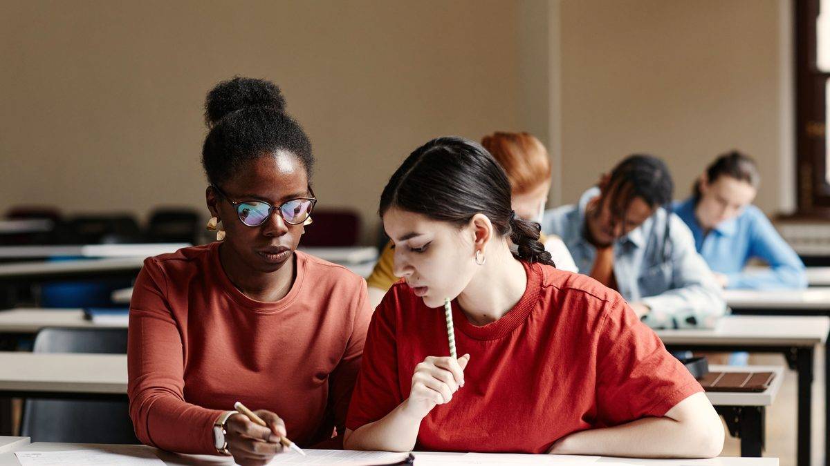 Deux adultes en formation prenant des notes côte à côte dans une salle de cours