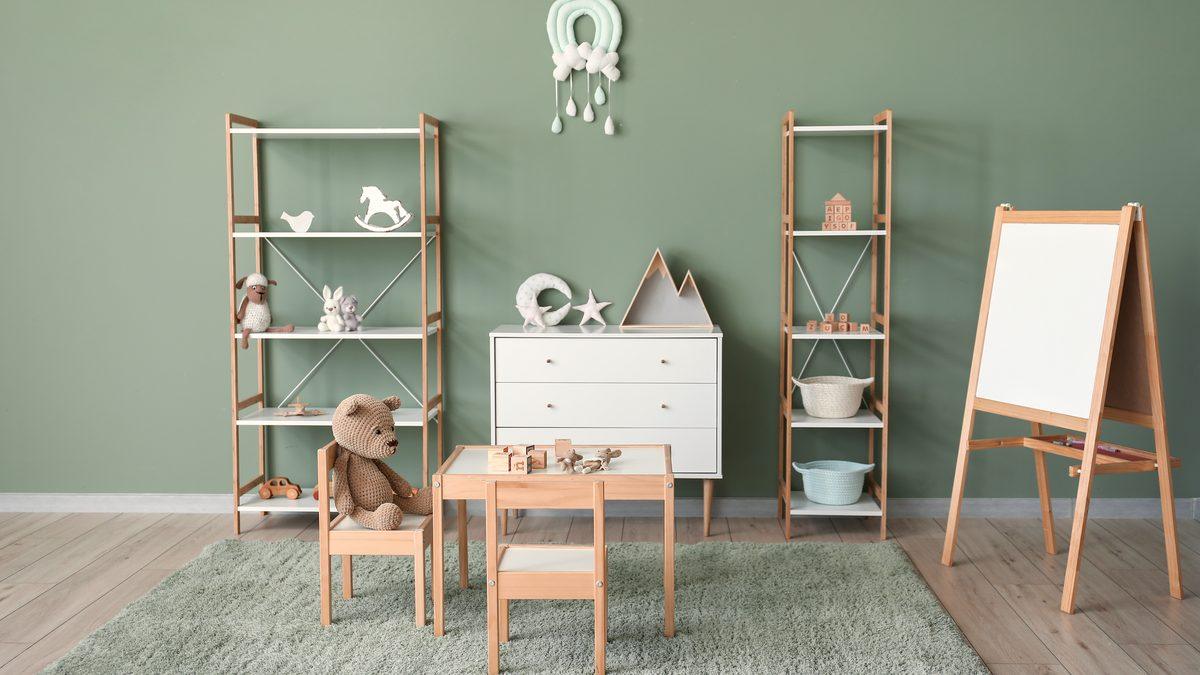 Salle d'activité de structure petite enfance avec étagères en bois, table basse et chevalet de peinture