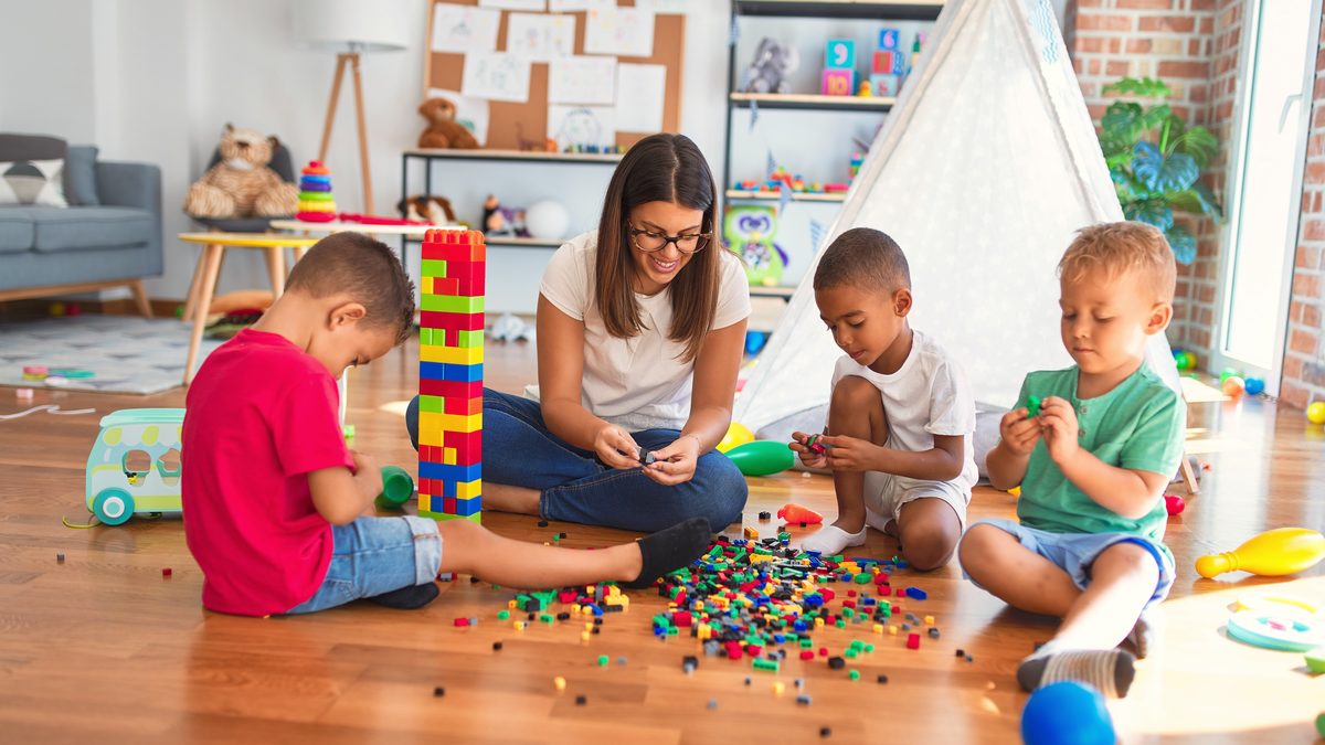 Professionnelle de crèche jouant avec de jeunes enfants dans une salle d'activités