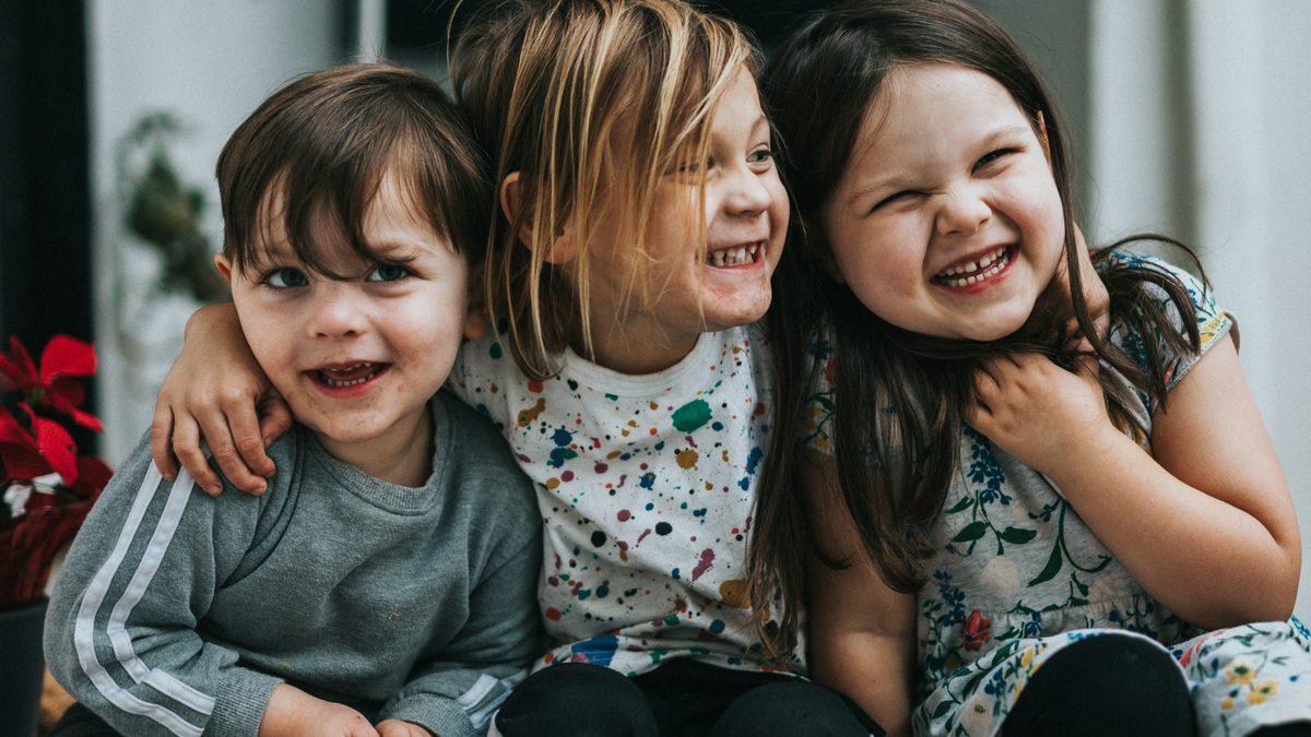 Trois jeunes enfants assis côte à côte en train de rire : l'accueil collectif, l'une des trois grandes options de mode de garde