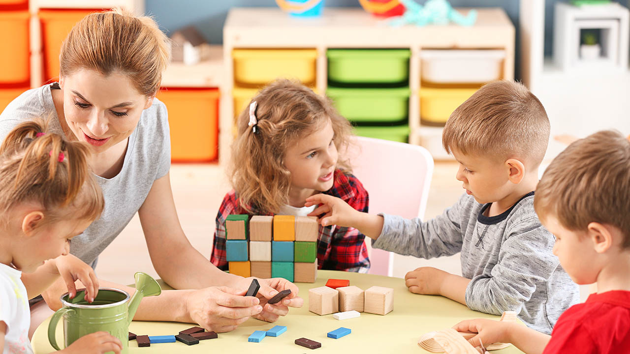 Professionnelle de crèche jouant aux jeux de construction avec de jeunes enfants