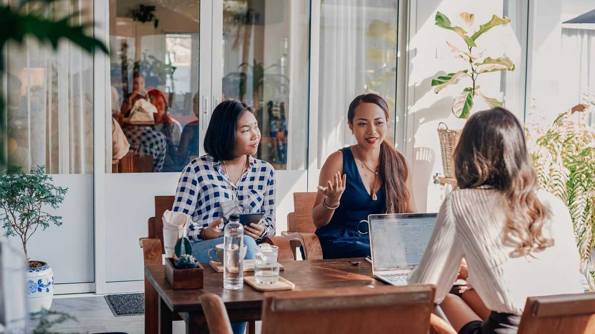 Trois professionnelles réunies autour d'une table pour rédiger ensemble un document de travail