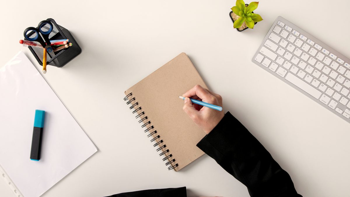 Candidate rédigeant son projet professionnel d'auxiliaire de puériculture sur un carnet