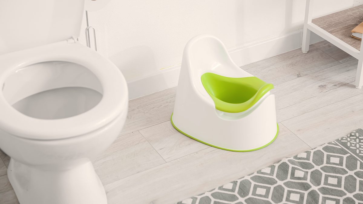 Petit pot d'enfant posé au sol dans une salle de bain lumineuse, symbole de l'apprentissage de la propreté