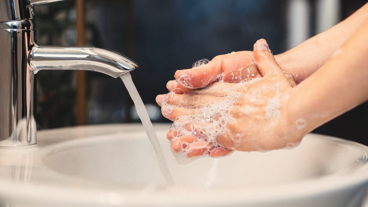 Jeune femme qui se lave soigneusement les mains avec du savon, geste d'hygiène de base