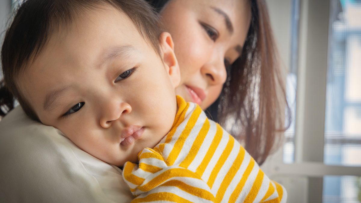 Professionnelle de crèche réconfortant doucement un jeune enfant qui pleure