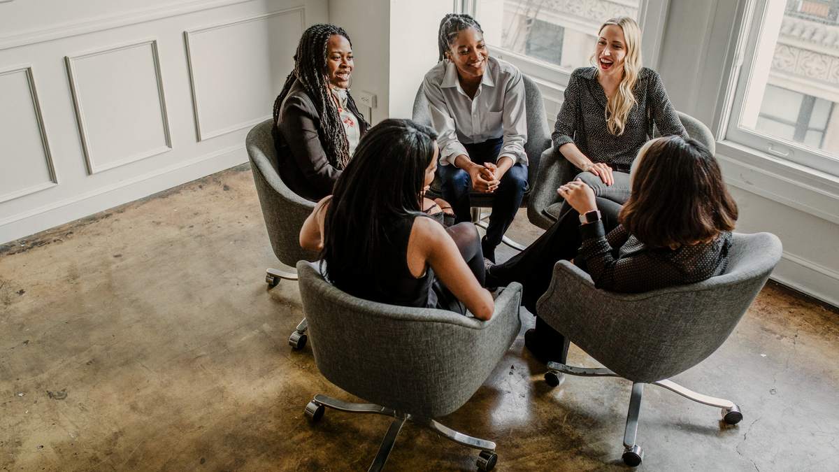 Équipe de professionnelles réunies en cercle pour une réunion de travail dans une salle lumineuse