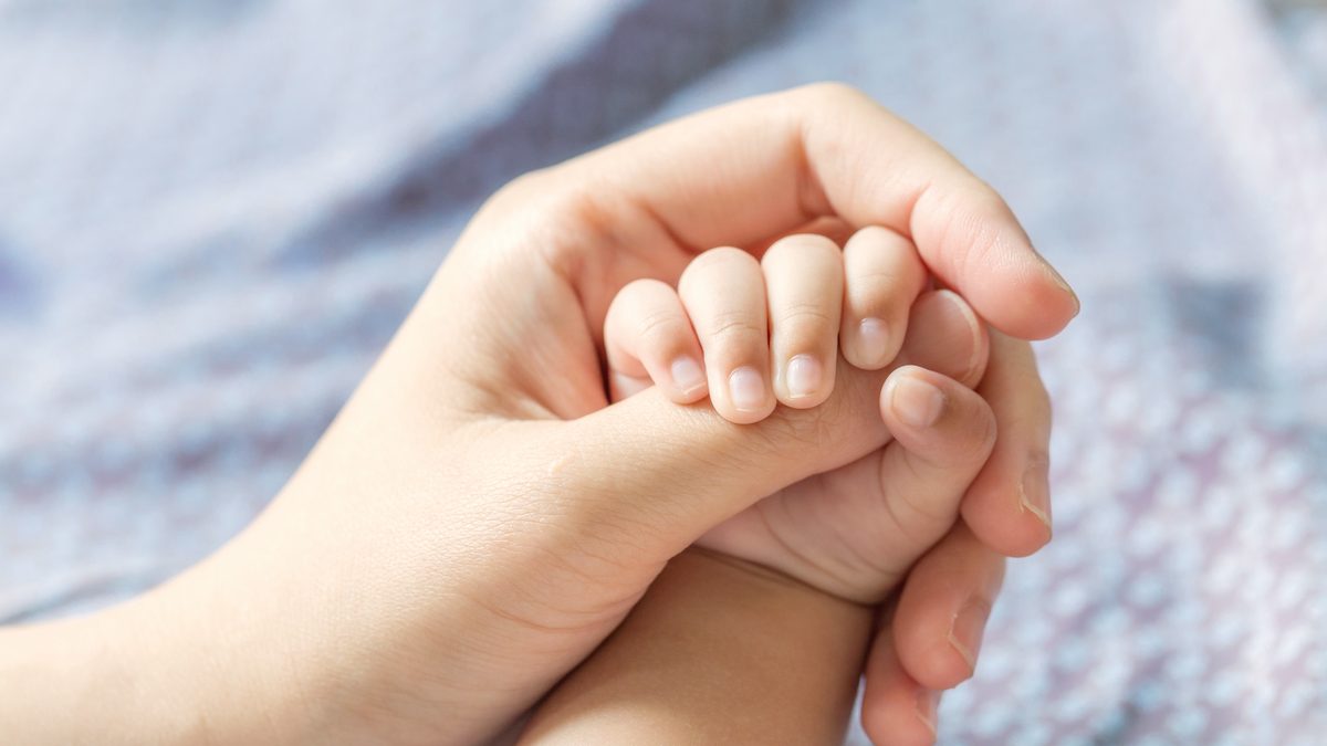 Le poing d'un nouveau-né enserre le doigt d'un adulte