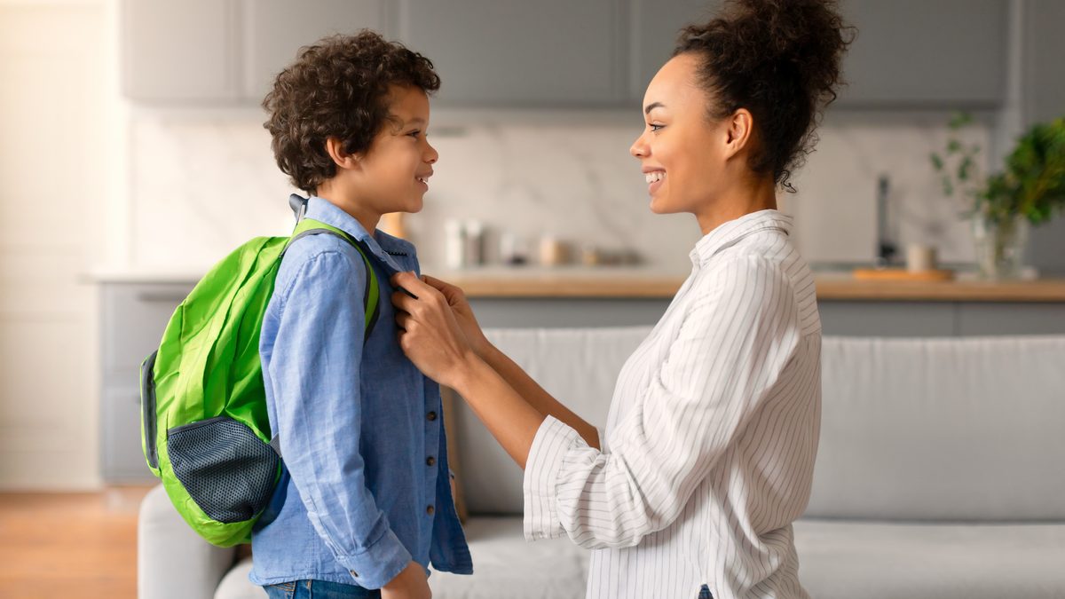 Une m&egrave;re ajuste le sac &agrave; dos de son enfant avant le d&eacute;part pour l'&eacute;cole
