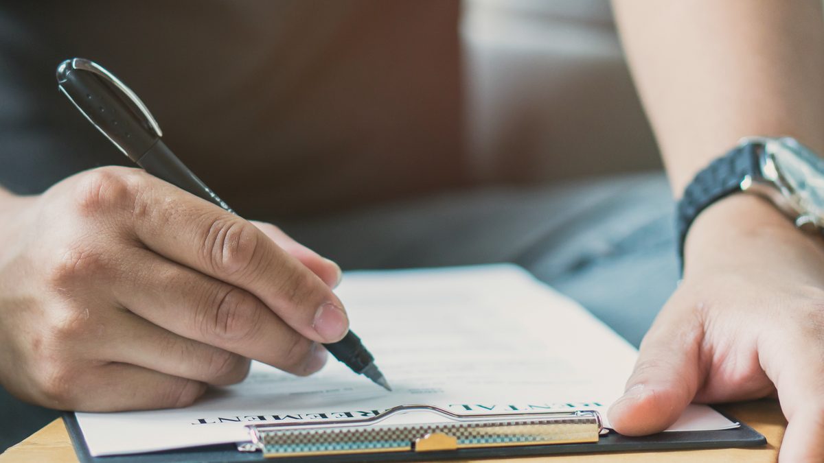 Mains d'une personne remplissant un formulaire administratif au stylo sur un porte-documents