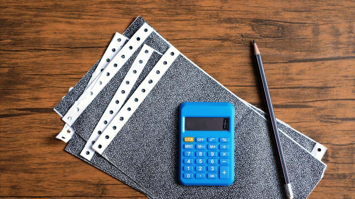 Bulletins de paie et calculatrice posés sur un bureau en bois