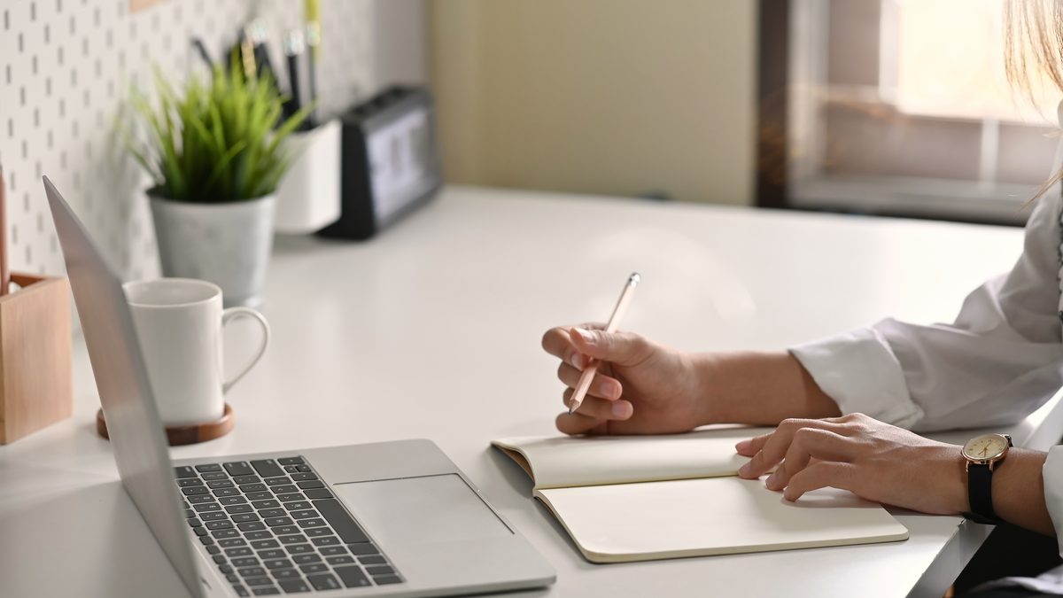 Professionnelle de la petite enfance rédigeant une transmission écrite sur un carnet