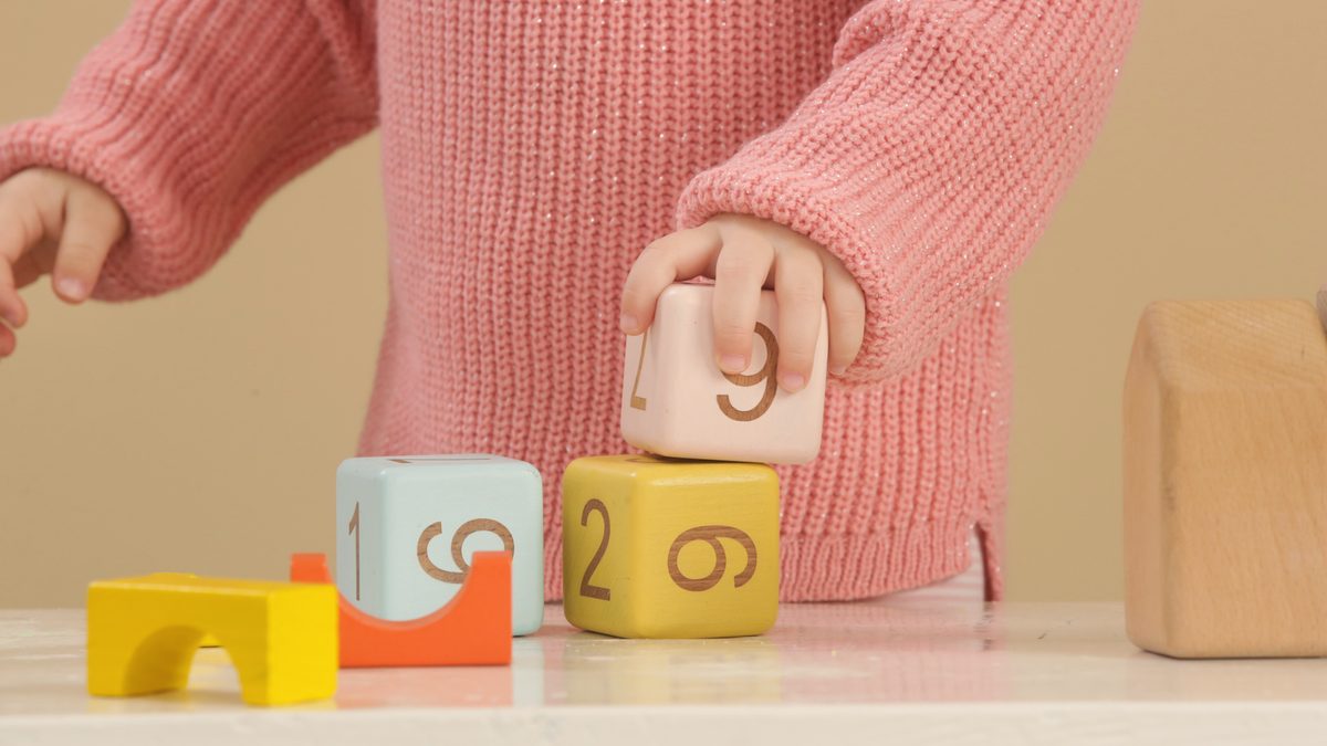 Les mains d'un tout-petit empilent des cubes en bois colorés sur une table