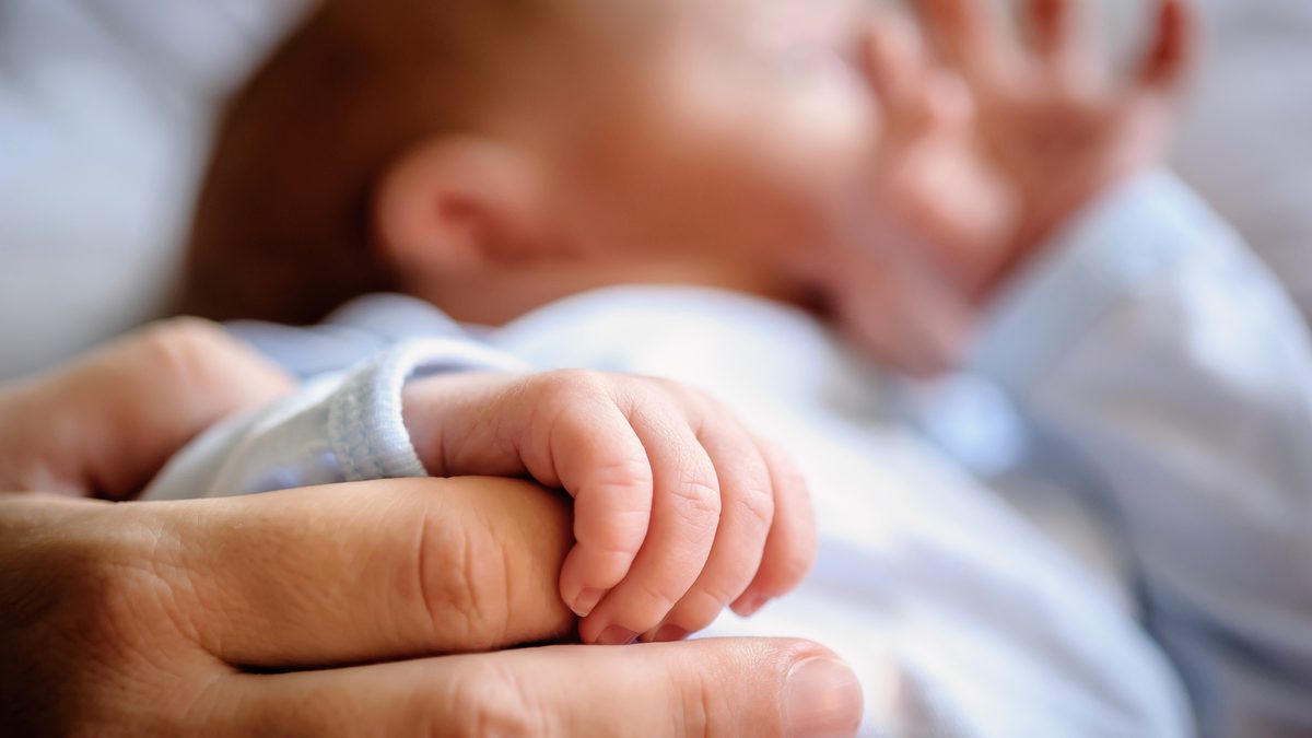 Gros plan sur la main d'un nouveau-né qui serre le doigt d'un adulte