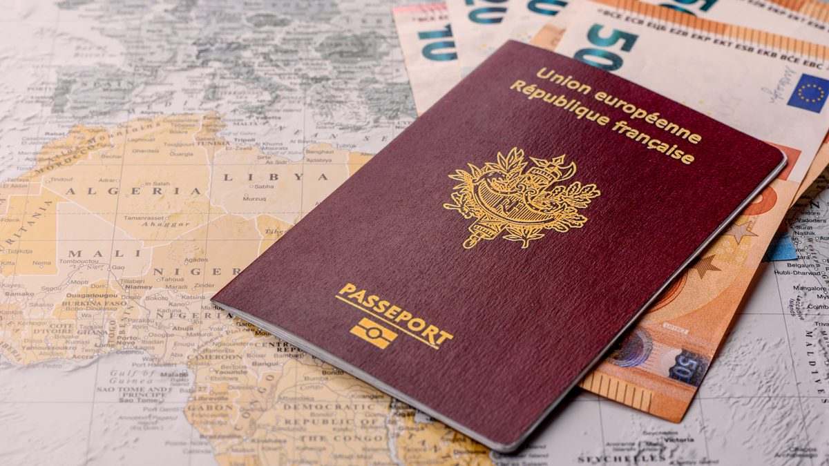 Passeport français posé sur une carte du monde à côté de billets en euros