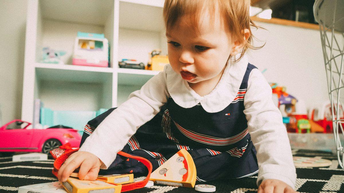 Jeune enfant jouant avec des jouets en bois dans un salon : le quotidien d'un accueil individuel chez une assistante maternelle ou une garde d'enfants à domicile